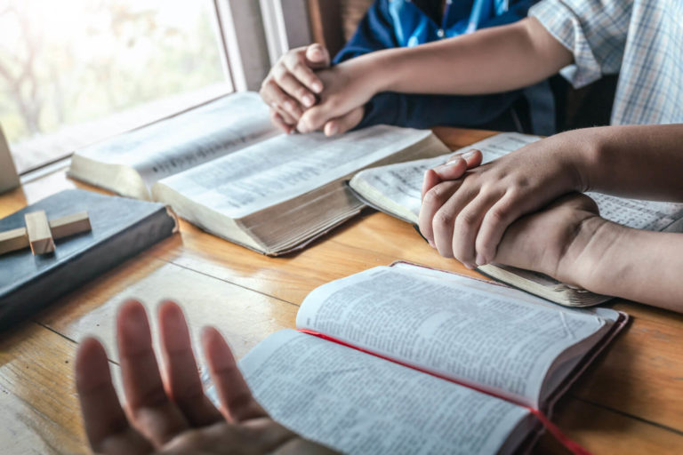 children gathered around table holding hands - glory gang family biblical truth